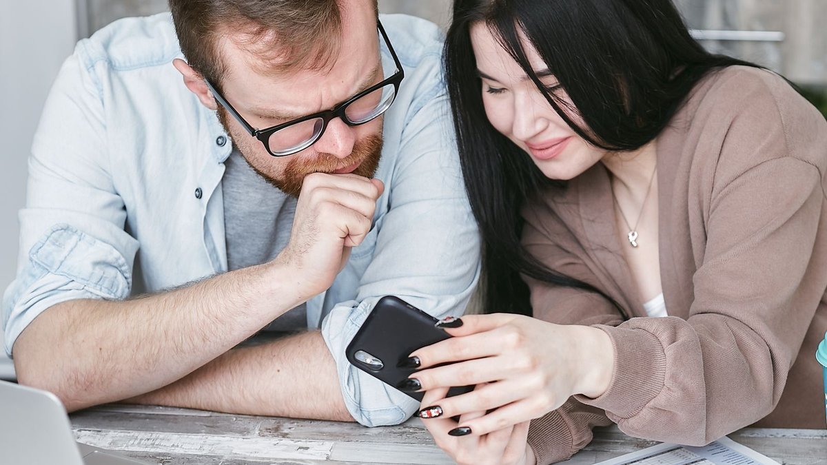 Couple reviewing financial papers with a phone