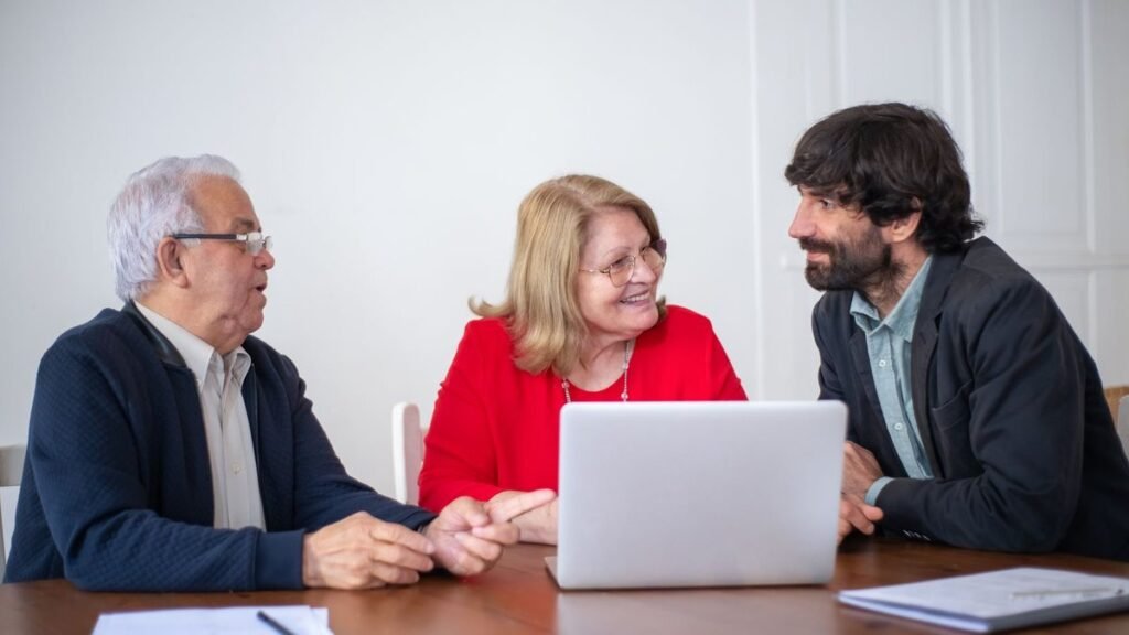 Older couple talking with an advisor at a table with a laptop