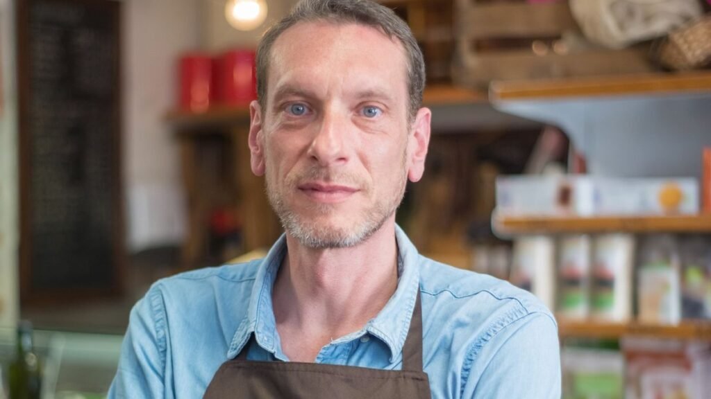 Confident shop owner in an apron with arms crossed